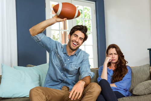 Couple in living room watching american football match on television